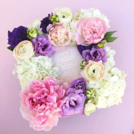 Floral wreath with pink, purple, and white blooms around a framed quote