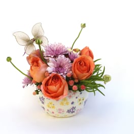 Orange roses and lavender blooms in a floral ceramic pot
