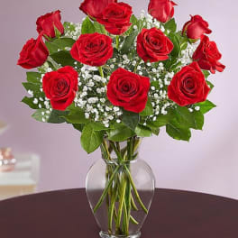 Red roses arranged in a clear glass vase with baby's breath