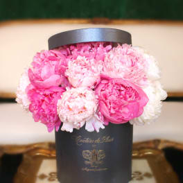 Pink peonies arranged in a black hat box