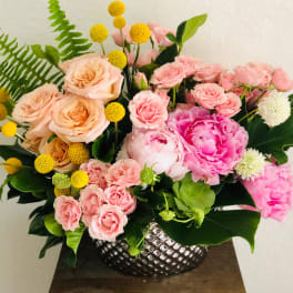 Pink and peach floral arrangement in a silver textured vase