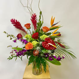 Tall tropical bouquet with roses, orchids, and bird of paradise in a glass vase