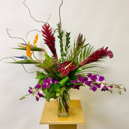 Tropical floral arrangement in a glass vase with purple orchids and red anthurium