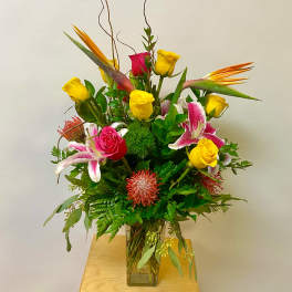 Mixed bouquet of yellow and pink roses with lilies in a glass vase