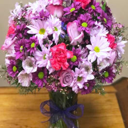 Bouquet of pink and purple flowers in a glass vase with a ribbon
