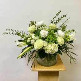 White floral arrangement in a glass vase with long green foliage