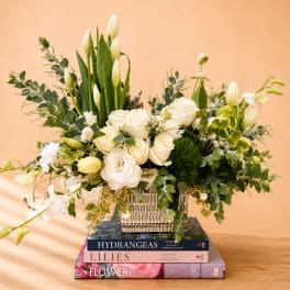 White roses and lilies arranged in a square vase with greenery