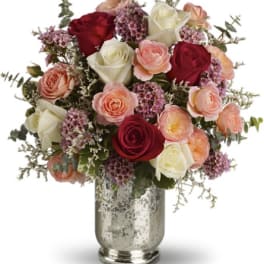 Mixed roses and small purple flowers arranged in a silver vase