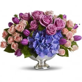 Purple and pink roses with blue hydrangea in a silver vase