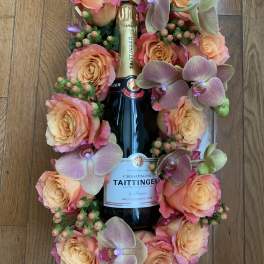 Champagne bottle surrounded by peach roses and orchids