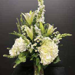 White lilies and hydrangeas arranged in a clear glass vase