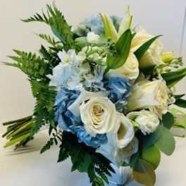 Bouquet of white roses, blue flowers, and lilies with greenery
