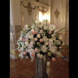 Large white and blush floral arrangement on a pedestal stand