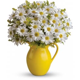 White daisy bouquet with yellow centers arranged in a bright yellow ceramic pitcher