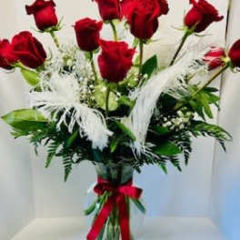 Bouquet of red roses in a clear glass vase with white feathers