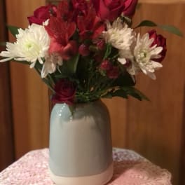 Bouquet of red roses and white daisies in a gray vase