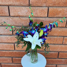 White lily and purple orchids in a glass vase