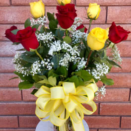 Bouquet of red and yellow roses in a glass vase with a yellow ribbon