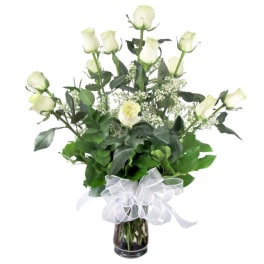 White roses in a glass vase with a white ribbon bow