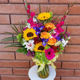 Colorful mixed bouquet in a glass vase with sunflowers and roses