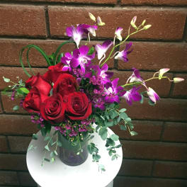 Bouquet of red roses and purple orchids in a glass vase