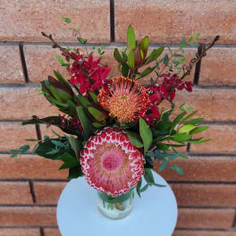 Pink and red protea arrangement in a clear glass vase