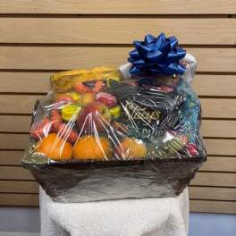 Gift basket of fruit and snacks wrapped in clear cellophane with a blue bow
