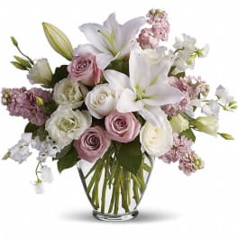 Pink and white bouquet with lilies and roses in a clear glass vase