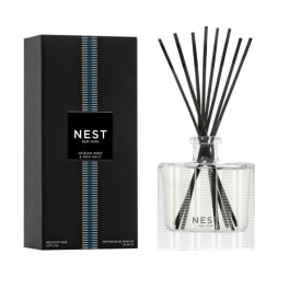 Reed diffuser in a glass bottle with black reeds and a black box