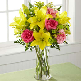 Yellow lilies and pink roses in a clear glass vase