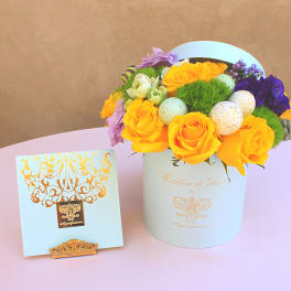 Yellow roses and purple flowers in a white hat box with decorative eggs