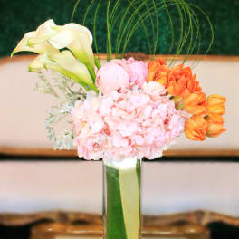 Pink and orange floral arrangement in a tall glass vase