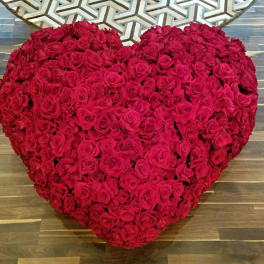 Heart-shaped arrangement of red roses on a wooden floor