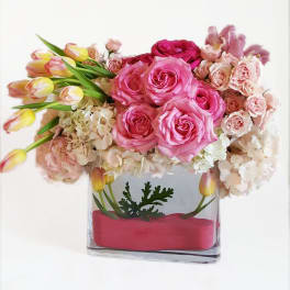 Pink roses and tulips arranged in a clear rectangular vase