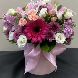 Pink and white mixed flower arrangement in a pink hatbox with ribbon