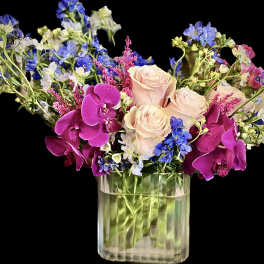 Pink roses and purple orchids in a clear glass vase