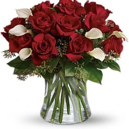 Bouquet of red roses and white calla lilies in a clear glass vase