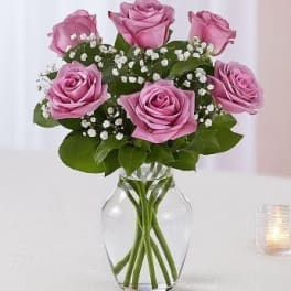 Pink roses arranged in a clear glass vase with baby's breath