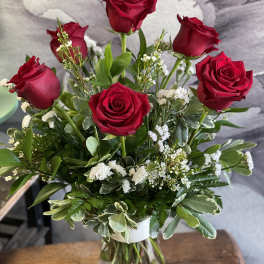 Red roses arranged in a clear glass vase with white filler flowers