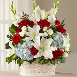 Basket arrangement of red roses, white lilies, and blue hydrangeas