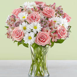 Pink roses and white daisies in a clear glass vase