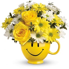 Yellow and white flowers arranged in a smiley-face mug