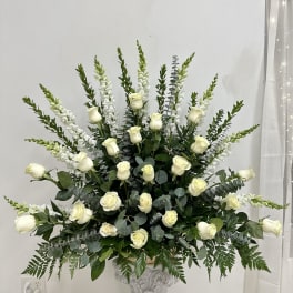 White roses and tall white snapdragons in a decorative pedestal vase