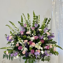 Large pastel floral arrangement in a white pedestal vase