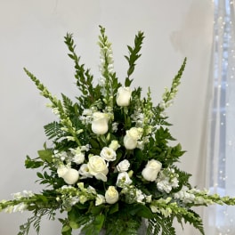 Tall white rose and snapdragon arrangement in a white pedestal urn