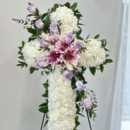 White floral cross with pink lilies and lavender roses on an easel