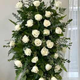 Tall standing arrangement of white roses and greenery on a black easel