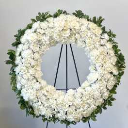 White floral wreath on a black stand