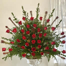 Large arrangement of red roses in a decorative pedestal vase