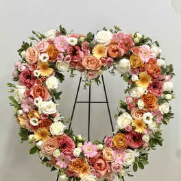 Heart-shaped floral wreath with pink, peach, white, and yellow blooms